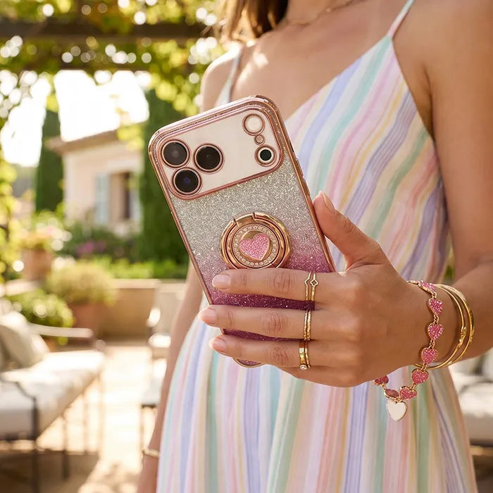 XYZ Super Shine Phone Case for iPhone 18 Pro Max in Pink — glittery chrome design with rotating heart ring stand and matching heart wrist strap in outdoor lifestyle scene all-groups